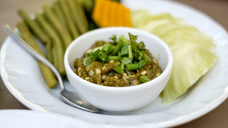 small bowl of nam prik noom surrounded by vegetables