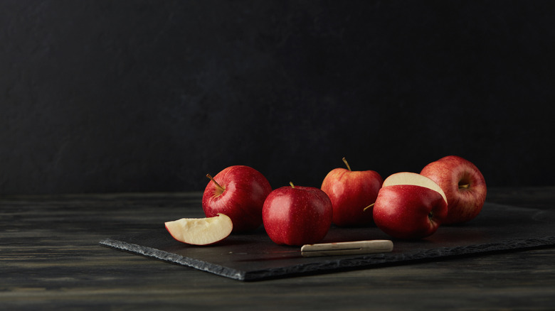 Sliced apples on a dark cutting board next to a knife
