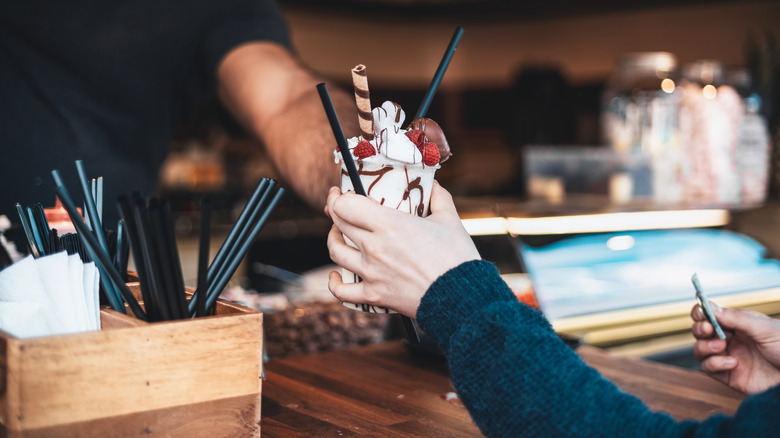 Customer receiving a sundae at an ice cream parlor