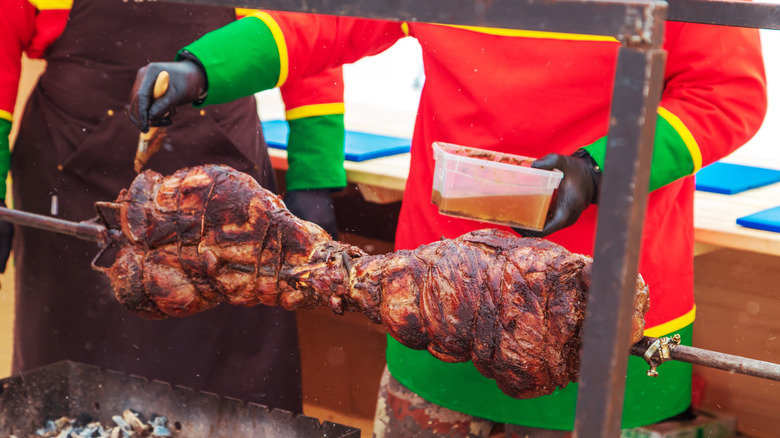 Men grill meat over coals at a traditional reindeer herders' festival