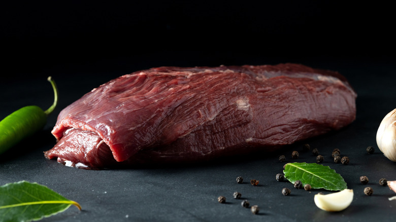 Reindeer meat on a cutting black board with seasonings
