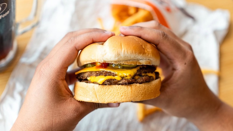 a diner holding a double cheeseburger from an A&W restaurant