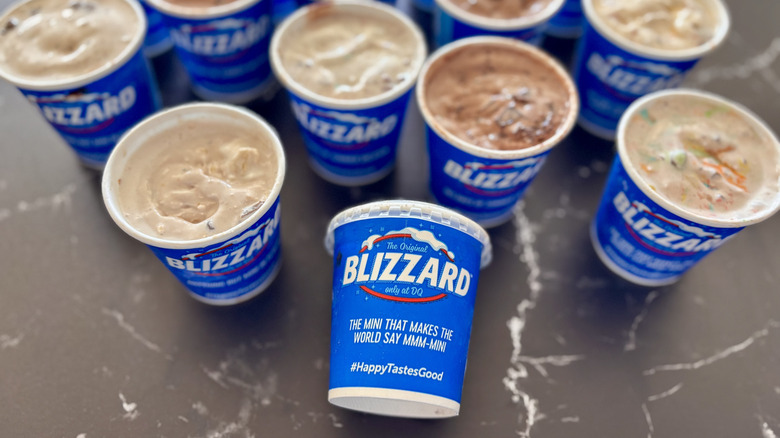 Several Dairy Queen Blizzards in blue cups on a table with one tipped over to show off the label