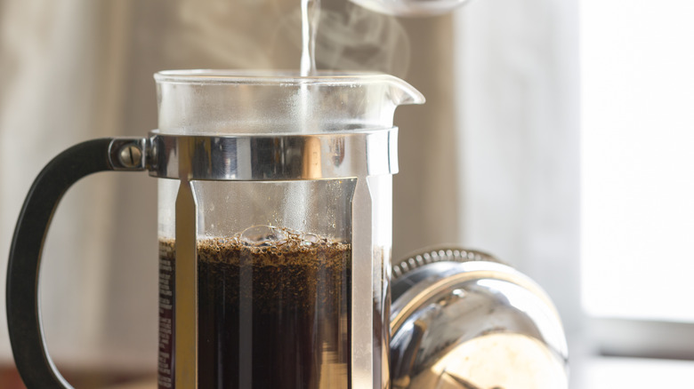 pouring hot water into french press coffee maker