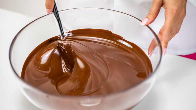 Hands stirring melted chocolate in bowl