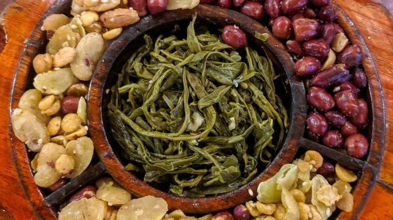 Top-down view of pickled tea served in a traditional compartmentalized dish with accompaniments