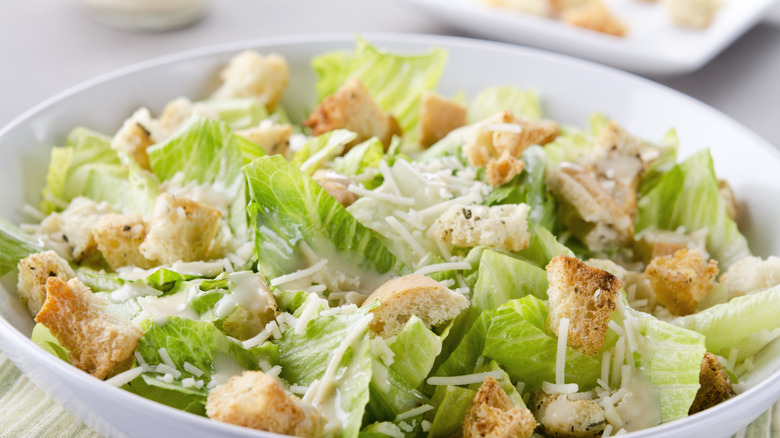 Close up of a Caesar salad with bright greens and dripping dressing