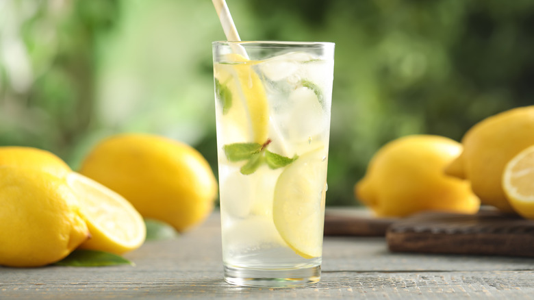 A glass of lemonade surrounded by lemons