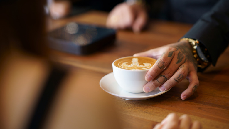 Person serving latte in a modern coffee shop