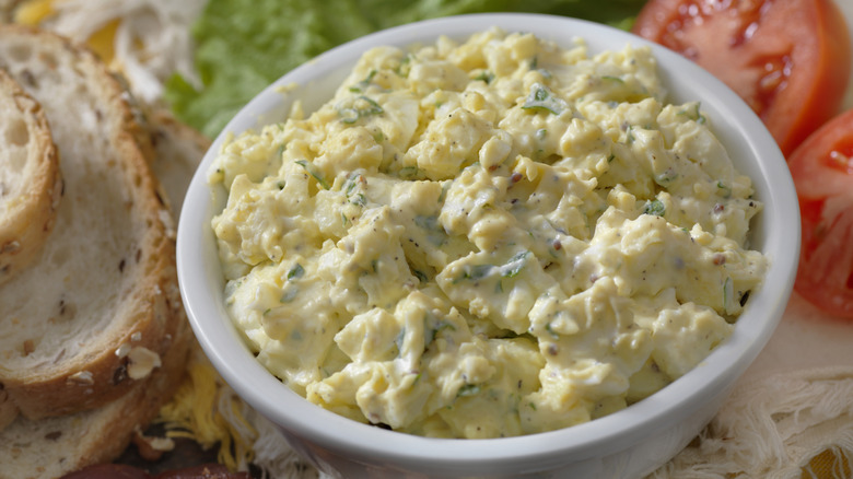 Egg salad in a bowl next to ingredients