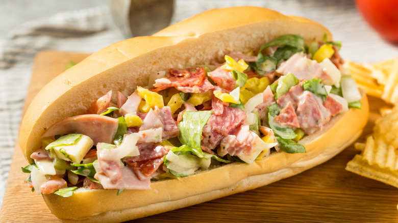 Chopped Italian sandwich sitting on board next to chips