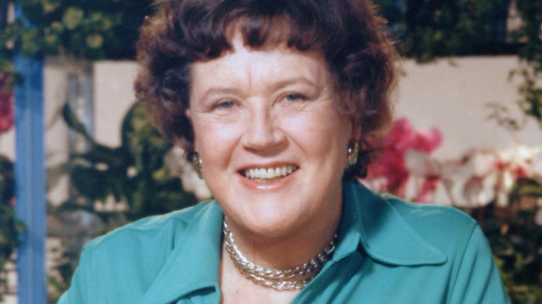 Julia Child smiling in front of outdoor garden background
