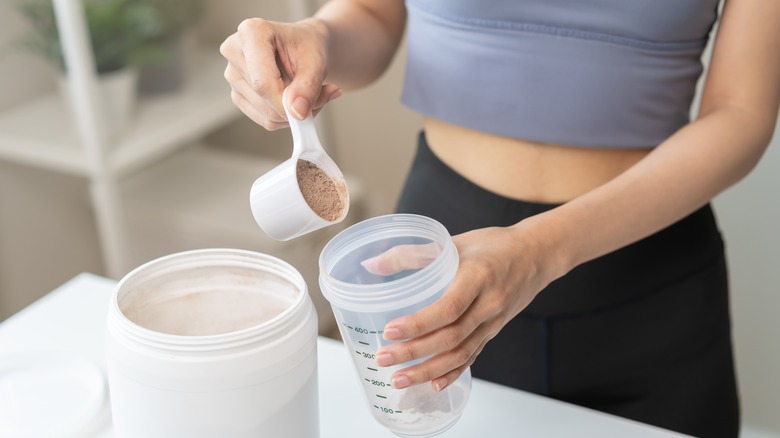 woman scooping powder into smoothie