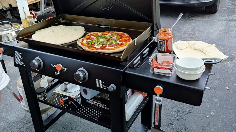 Two pizzas cooking on a Blackstone griddle.