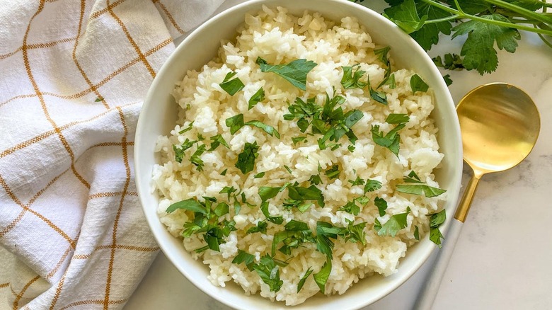 Brailian rice garnished with cilantro and a gold spoon
