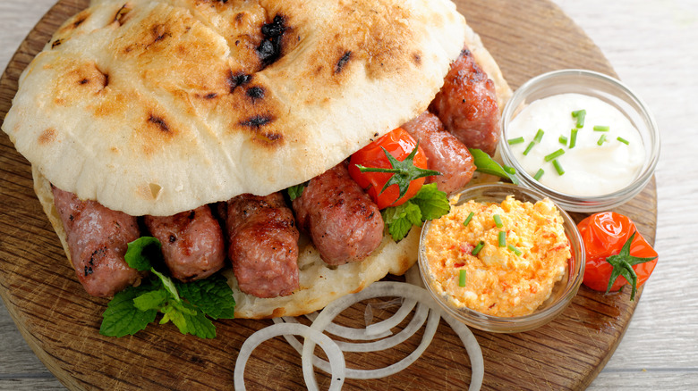 A Serbian cevapi sandwich with toppings and garnishes