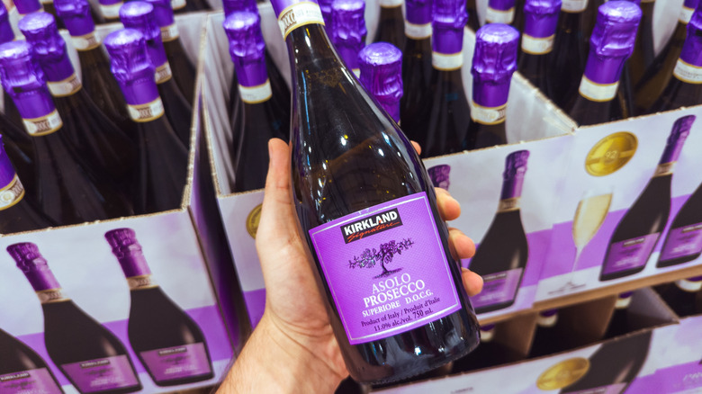 A person holding a bottle of Kirkland Signature Asolo Prosecco in a Costco store