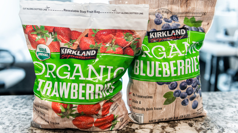 A bag of Kirkland Signature frozen strawberries and a bag of Kirkland Signature frozen blueberries next to each other on a counter