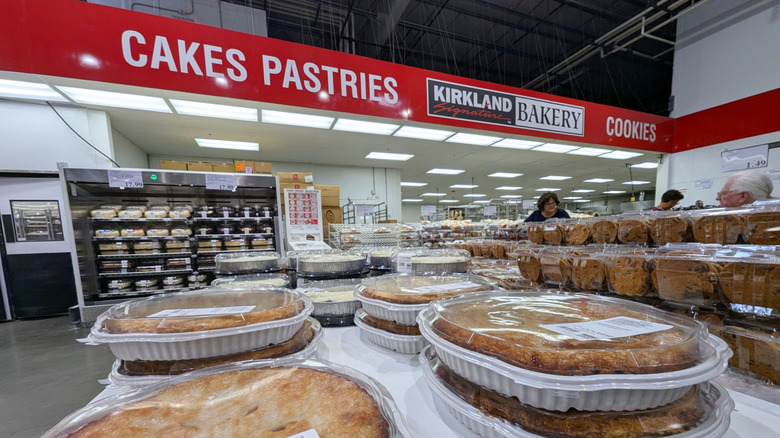 Costco's bakery department with customers and stacks of pies, cookies, cakes