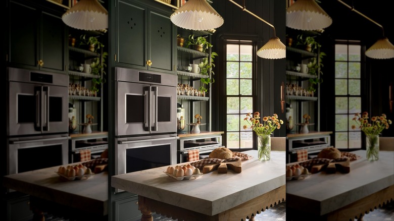 Kitchen with dark green cabinetry and walls, white marble countertop, and natural wood accents