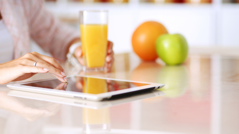Woman's hand using tablet in kitchen