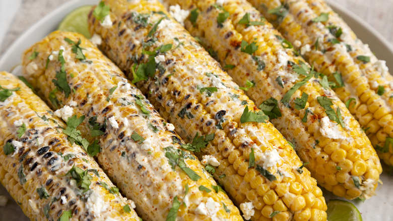 corn slathered in dressing and topped with herbs