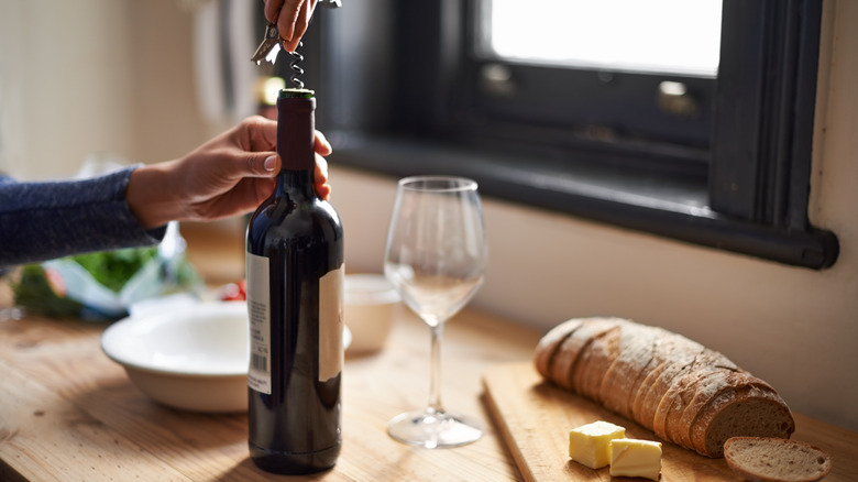 woman pulling the cork on wine bottle