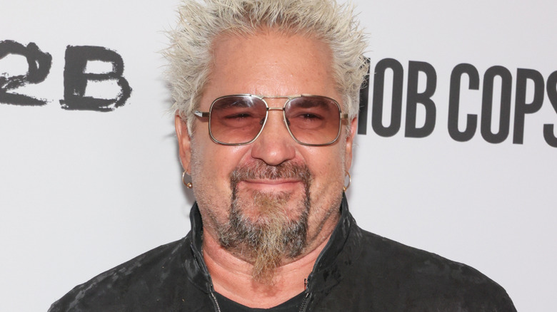 Guy Fieri on a red carped in a black jacket