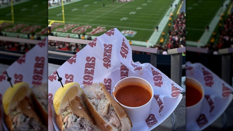 Fan holding Crab Sammies sandwich in front of field at Levi's stadium