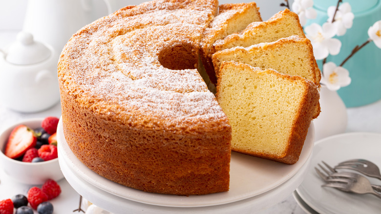 Closeup view of sliced lemon chiffon cake on a cake stand, topped with powdered sugar
