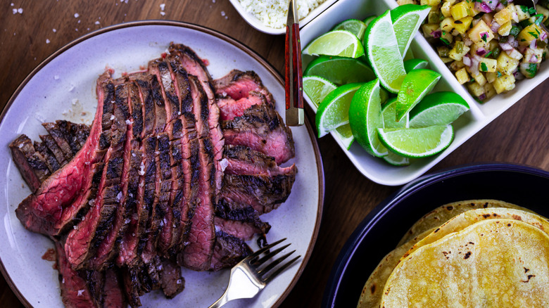 marinated sliced flank steak at taco bar with lime wedges and other ingredients