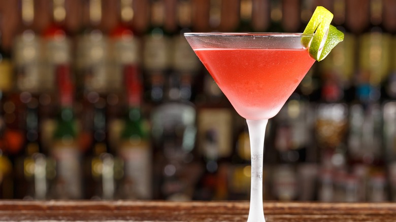 A Cosmopolitan cocktail garnished with lime on a bartop