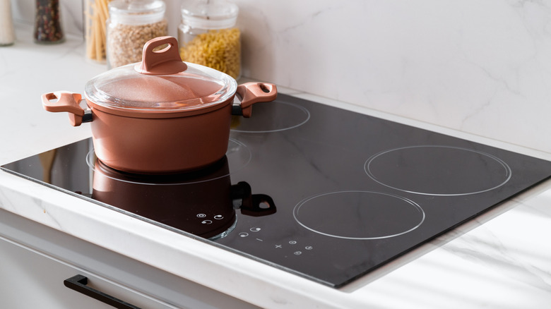 A pink colored pot sitting on a clean induction stove