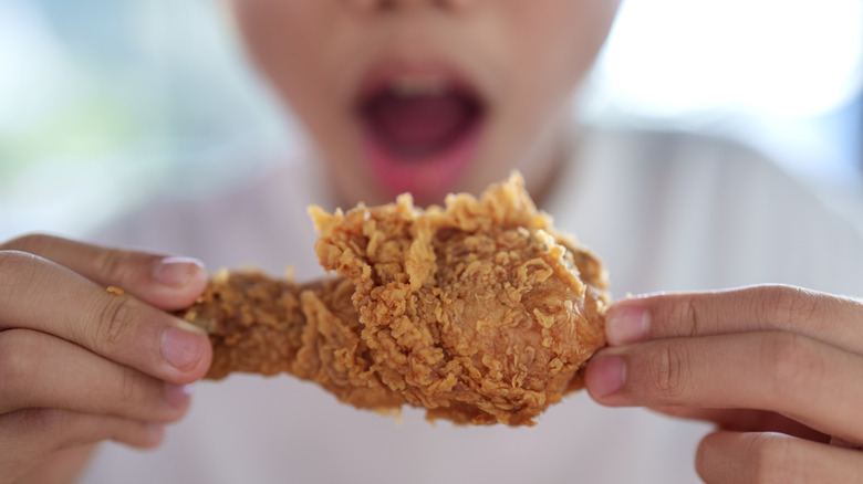 A person holding fried chicken