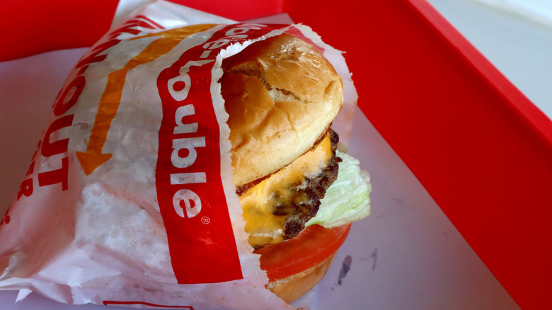 A Double-Double wrapped in paper on a tray at In-N-Out