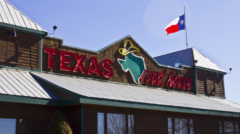 Texas Roadhouse sign on front of building with Texas flag