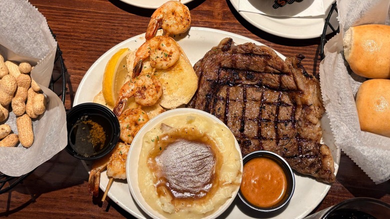 Plates with peanuts, steak, shrimp, mashed potatoes, and rolls at Texas Roadhouse