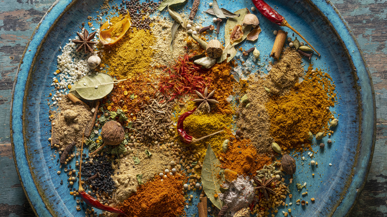 A variety of ground and whole spices on a plate