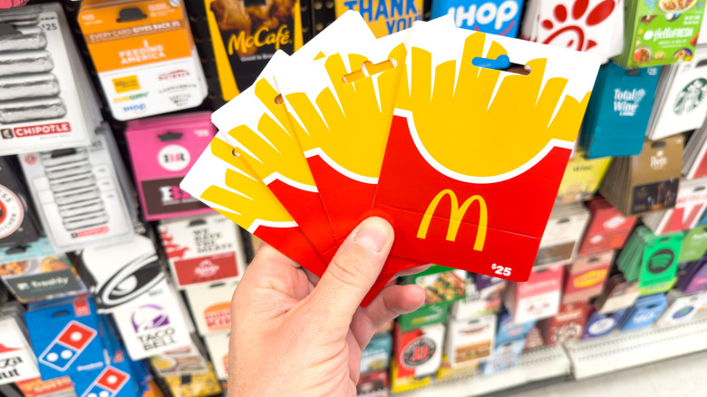 hand holds multiple McDonald's gift cards in front gift card display