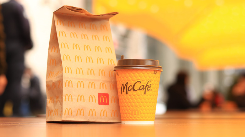 McDonald's paper bag and McCafé cup against blurred background