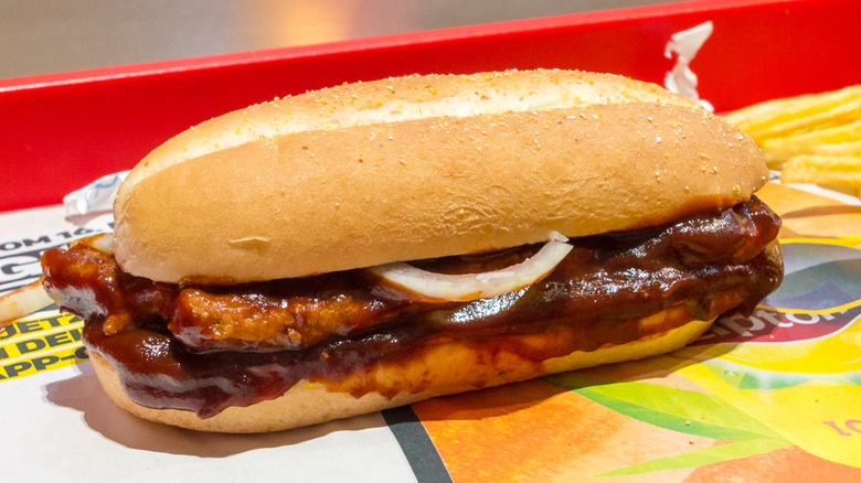 McDonald's McRib sandwich sitting on red tray with printed paper lining