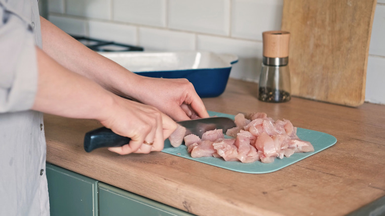 Person cutting chicken pieces countertop