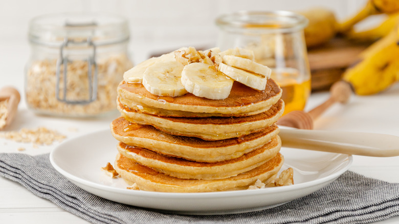 Pancakes stacked with sliced bananas and syrup