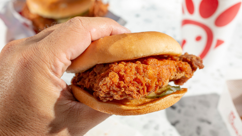 A hand holds a Chick-fil-A sandwich.