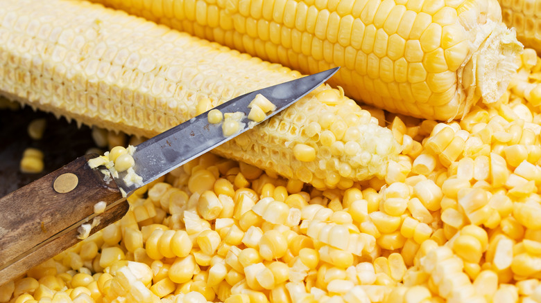 Knife cutting kernels off corn on the cob