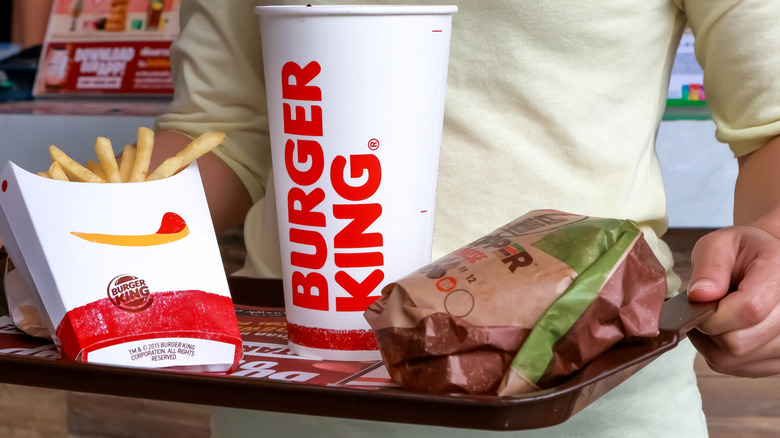 Person holding a tray of Burger King food and drink