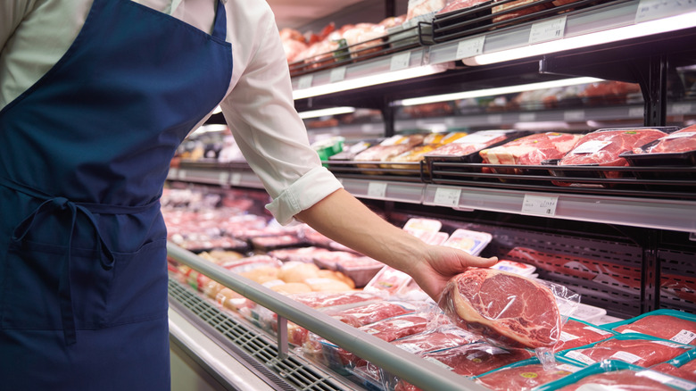person shopping for steak in grocery store