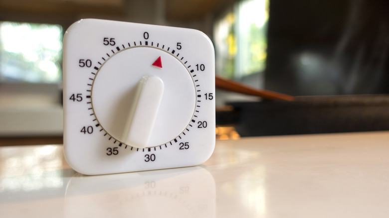 White kitchen timer with a red marker on a smooth beige counter