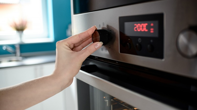 hHand setting temperature on oven