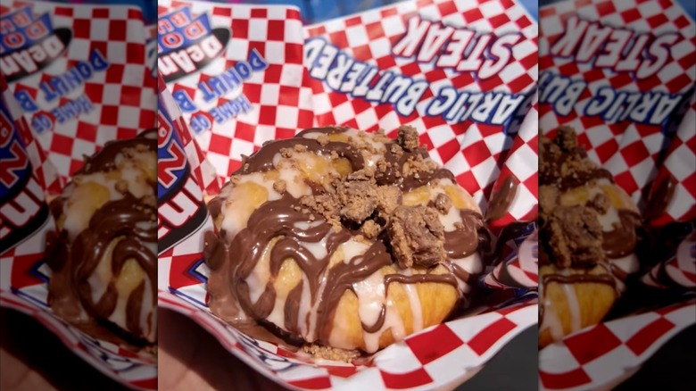 Reese's Pieces Donut Burger from DeAnna's Donut Burger sitting in basket lined with red and white checkered paper.